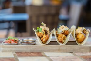 Baja fish tacos on a wooden board with salsas at Solomon's Landing Cabo San Lucas