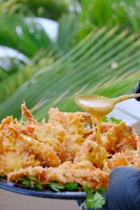 Coconut shrimp being drizzled with house sauce at Solomon's Landing