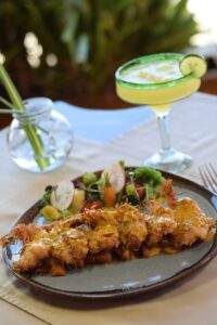 Coconut shrimp plate with a margarita on a set table at Solomon's Landing