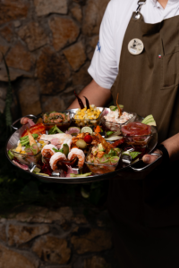 Server presenting a large seafood platter against a stone wall at Solomon's Landing