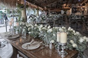 Long banquet table set with white roses and candles for an event at Solomon's Landing