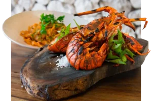 Wood-grilled whole lobster plated on a rustic board with herbs and sea salt
