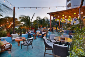 Open-air lounge terrace with string lights and palms at Tres Sirenas, Cabo San Lucas