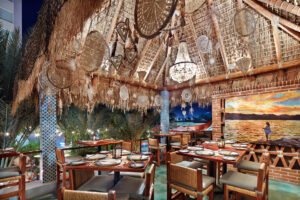 Palapa dining room with chandeliers and a sunset mural at Tres Sirenas, Cabo San Lucas
