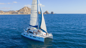 Leopard sailing catamaran underway off Cabo San Lucas with Land's End in the distance