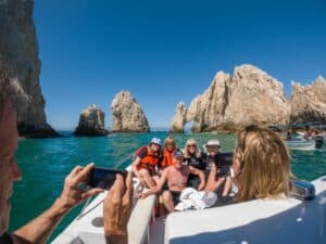 Cabo Trek guests aboard a small boat beside the Arch of Cabo San Lucas