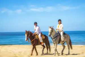 Couple on horseback along the Pacific beach during the Cactus Tours ride