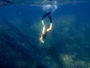 Freediver descending above a school of fish in Cabo San Lucas