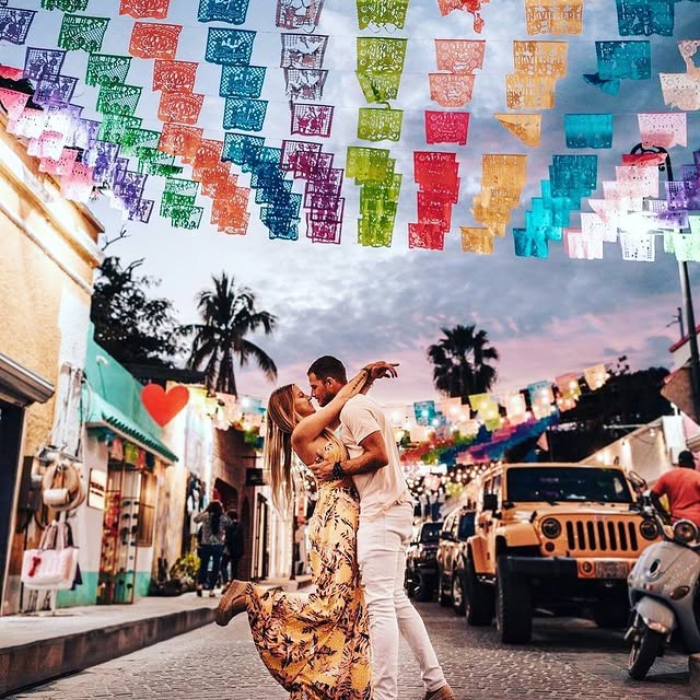 Couple dancing on a San José del Cabo street under rows of papel picado at dusk