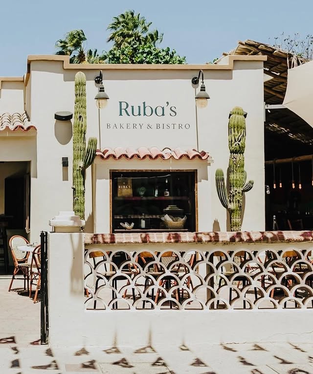 Whitewashed facade of Ruba's Bakery and Bistro with cacti and a tiled bench in San José del Cabo