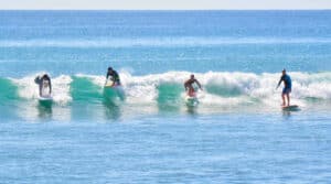 Surf coach helping a beginner stand on a wave at Costa Azul