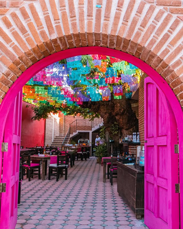 Pink arched doorway opening onto a courtyard hung with papel picado in San José del Cabo