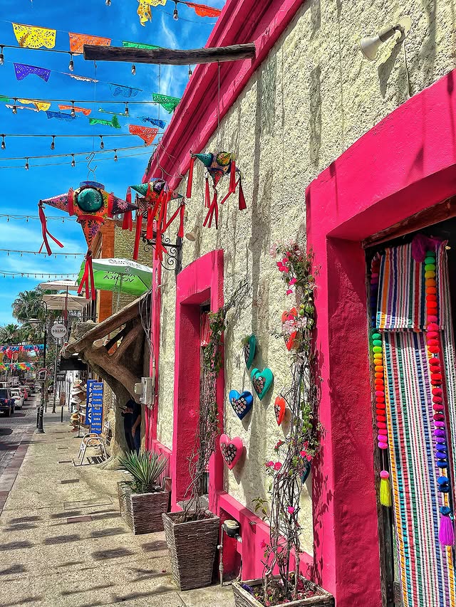 Pink shopfront street in the San José del Cabo Art District hung with crafts and papel picado