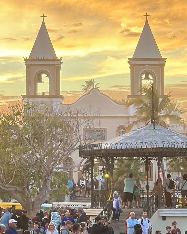 The twin bell towers of the San José del Cabo mission above the plaza kiosk at sunset