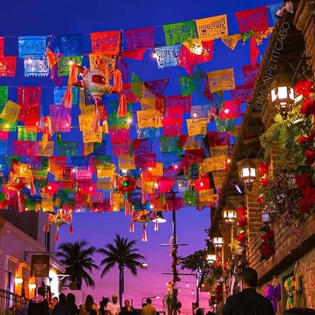 Papel picado and hanging lanterns strung over a San José del Cabo street at dusk