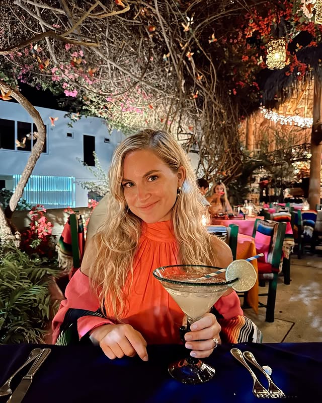 Guest holding a margarita at a plant-filled courtyard restaurant in San José del Cabo