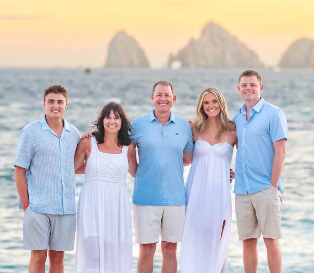 Family of five on the sand at sunset with the Arch of Cabo San Lucas behind them