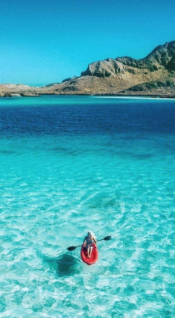 A single red kayak on the clear turquoise water of a Baja bay
