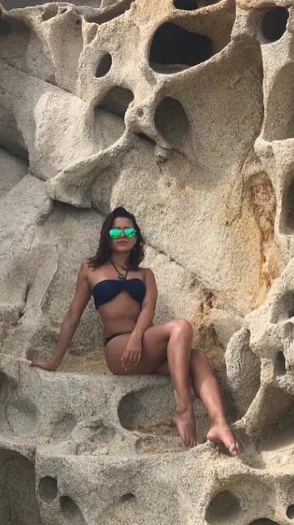 Woman seated in the wind-eroded rock formations beside Lovers Beach