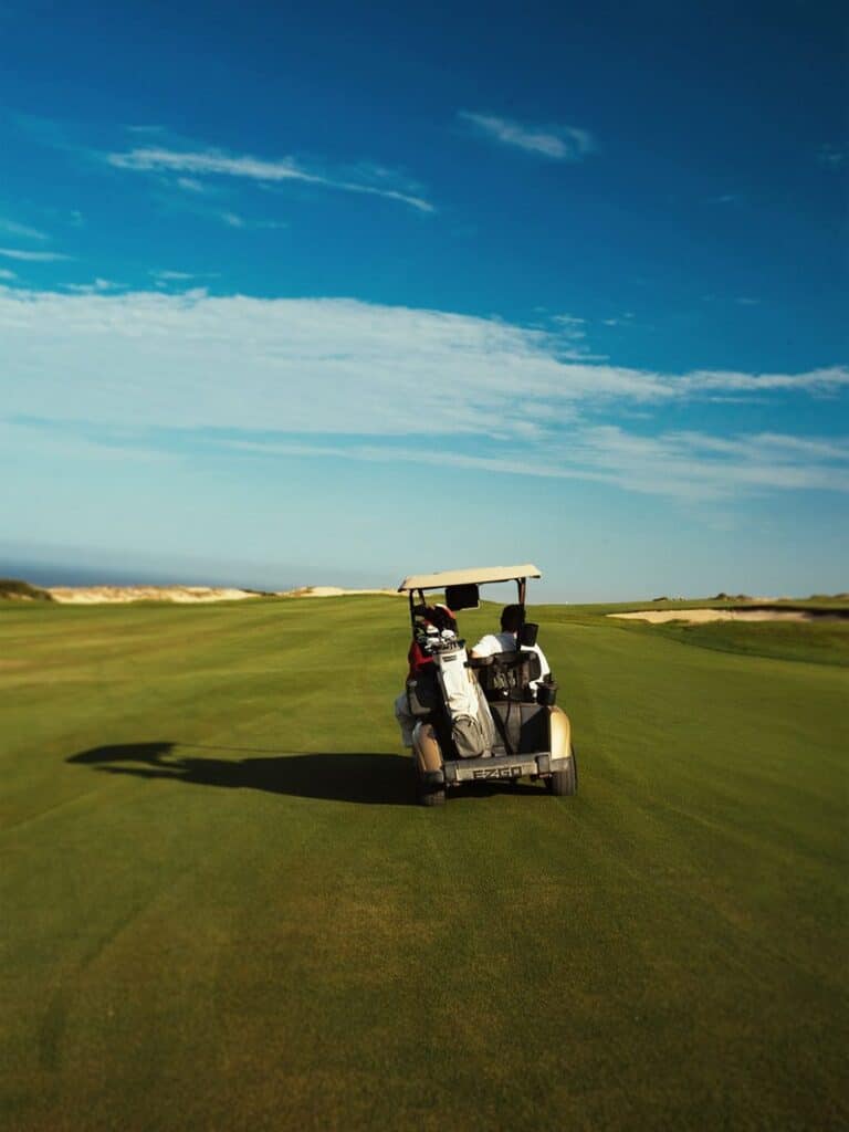 A golf cart alone on the fairway at Quivira Los Cabos under a wide pale sky