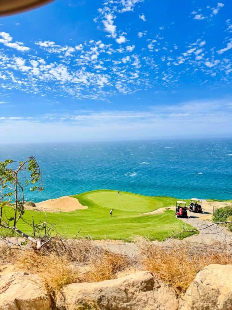 A green perched above the Pacific at Quivira Golf Club, tall clouds overhead