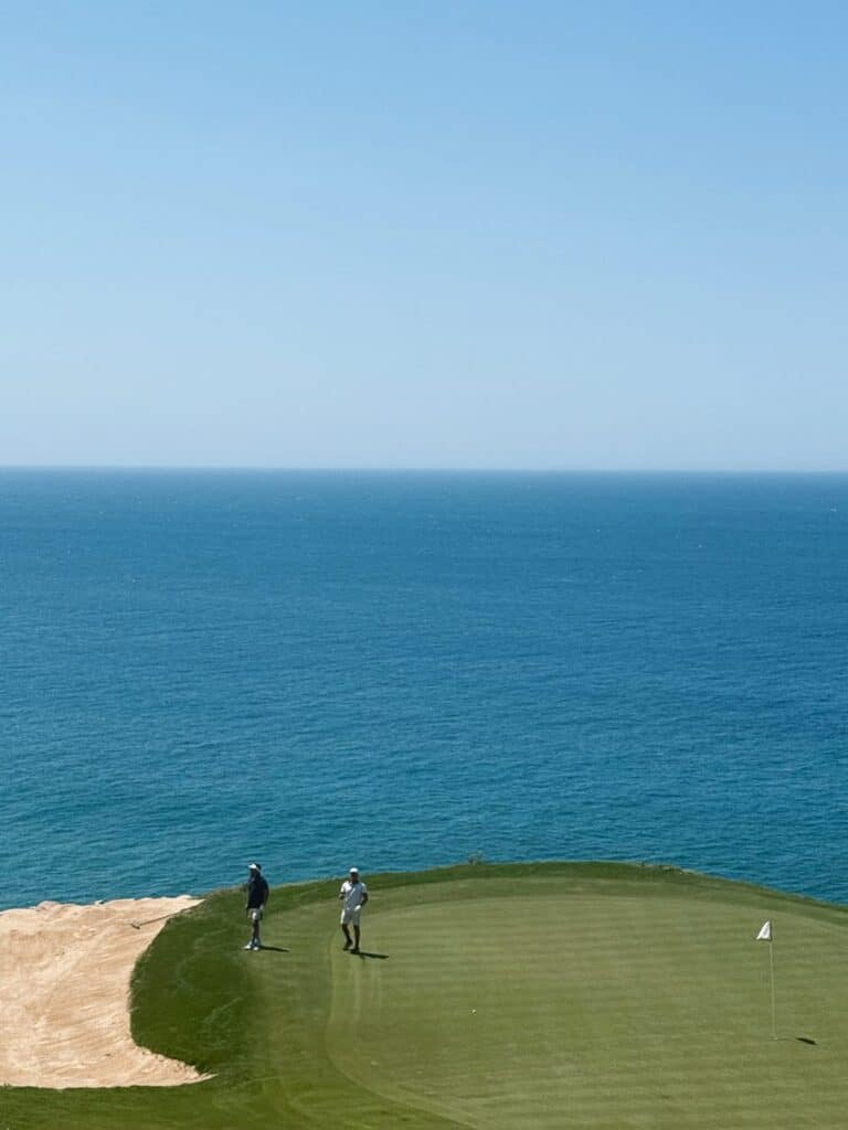 Two players on a clifftop green with the sea filling the frame
