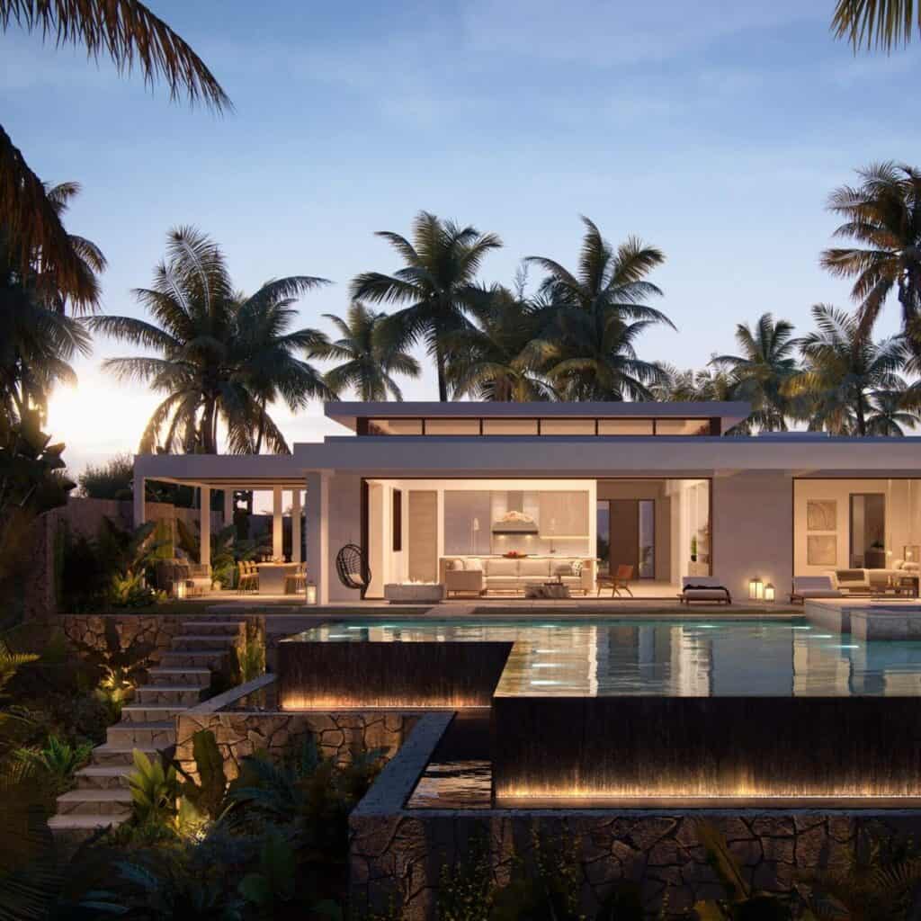 A villa lit from within at dusk behind the palms
