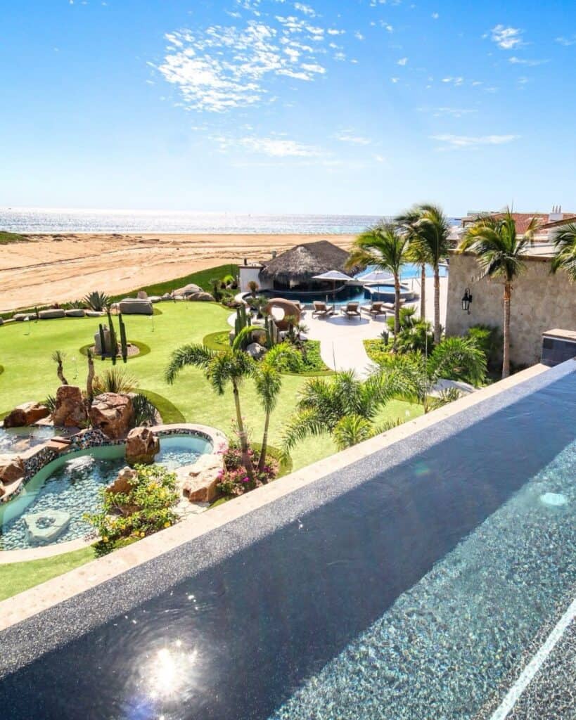 A pool and green meeting the dunes above the Pacific