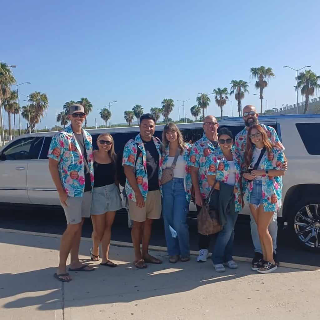 A group of travellers in matching shirts standing beside their van before a Los Cabos transfer.