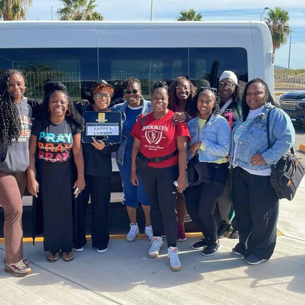A group of travellers standing together beside their shuttle in Los Cabos.