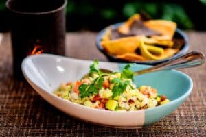 Ceviche with avocado, tomato and cilantro in a two-tone bowl, with tortilla chips at 7 Seas