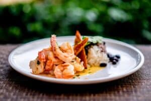 Shrimp with white rice, black beans and fried plantain on a white plate at 7 Seas