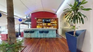 The deck bar at Baja Lobster Co., with a turquoise tiled counter, blue bar stools and a back bar of bottles on a red wall