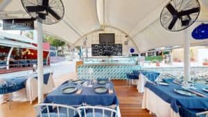 The deck at Baja Lobster Co. under its white canopy, with the restaurant sign and the tiled oyster bar counter at the back