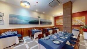 The air-conditioned dining room at Baja Lobster Co., with wave photographs and a fish mural made of small white plates