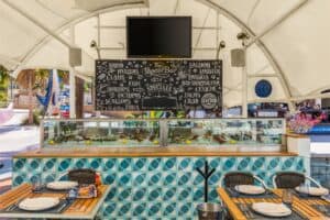 The oyster bar at Baja Lobster Co., a chilled seafood display on a tiled counter under a hand-drawn chalkboard
