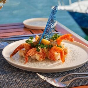 Shrimp plated with a blue lace garnish on a table by the water at Baja Lobster Co.