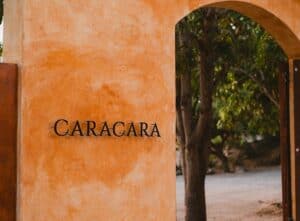 The Caracara name on an orange stucco wall beside an arched wooden doorway at Villa Santa Cruz