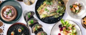 Grilled romaine Caesar, a beet salad, corn empanadas and other plates on a table at Caracara, seen from above