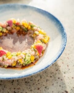 A ring of diced fish ceviche with avocado and colorful vegetables in a blue-rimmed bowl at Casamarte