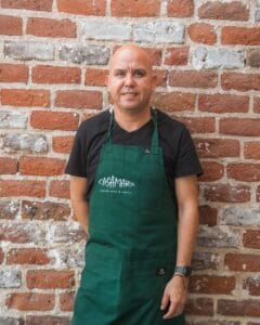 Chef Héctor Palacios in a green Casamarte apron against a brick wall