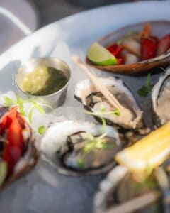 Raw oysters on crushed ice with lime, a cup of green sauce and a dish of red shellfish at Casamarte
