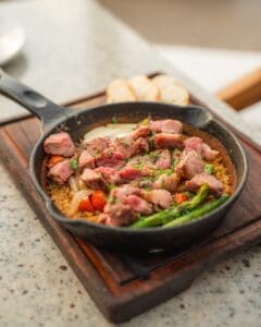 Rice with grilled rib eye, asparagus and cherry tomatoes in a cast-iron skillet, with toasted bread, at Casamarte