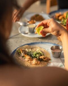 A diner squeezing lime over a battered seafood taco on a flour tortilla at Casamarte