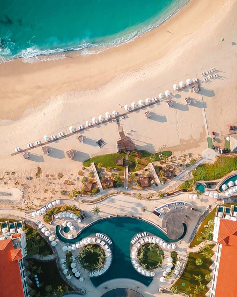 The beach, pools and palapas of Hilton Los Cabos seen from above