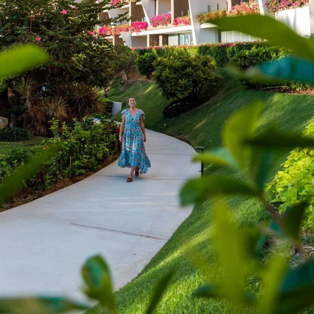 A woman walking a garden path lined with bougainvillea at Grand Velas Los Cabos