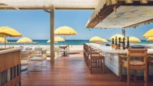 The tiled bar and shaded wooden terrace at Delphine, Costa Palmas, looking out to yellow umbrellas and the Sea of Cortez