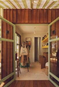The green French doors opening into La Boutique at Delphine, with hats, tote bags and resort wear on display