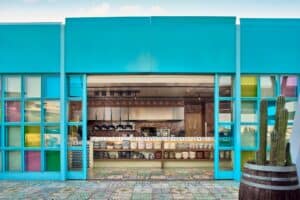 The turquoise glass front of El Barrio open to the kitchen, with stacks of handmade plates and bowls on the shelves below the counter
