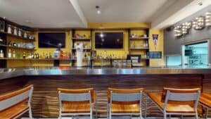 The steel-topped bar at Golden Legends with bar stools, TV screens and football helmets on the shelves